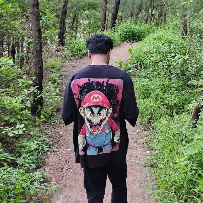 Person walking through a forest wearing a black t-shirt with a colorful graphic design.