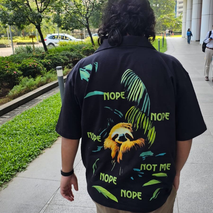 Person wearing a black shirt with a sloth graphic and 'NOPE' text, walking outdoors.